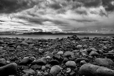 Scenic view of rocky beach against cloudy sky