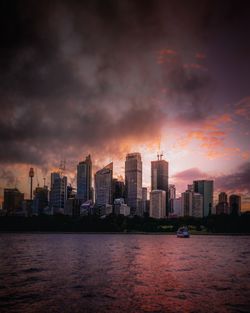 Buildings by sea against sky during sunset