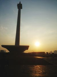 Silhouette airplane on airport against sky during sunset