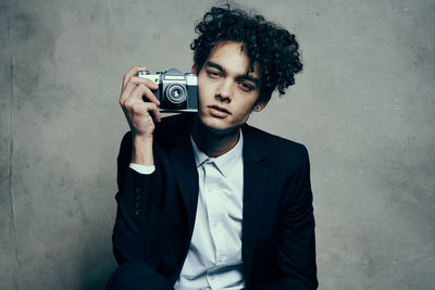 Portrait of young man photographing against wall