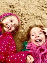 Portrait of happy girls lying on sand at beach