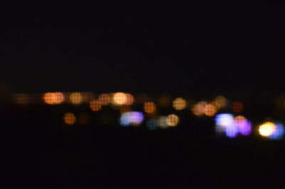 Defocused image of illuminated cityscape against sky at night