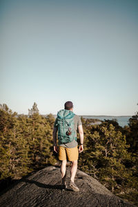 Rear view of man looking at camera against sky