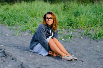 Full length portrait of mid adult woman sitting at beach