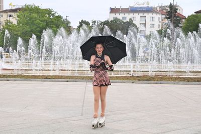 Full length of woman with fountain in city