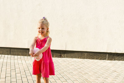 Portrait of young woman standing against wall