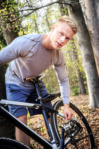 Portrait of muscular man with bicycle in forest