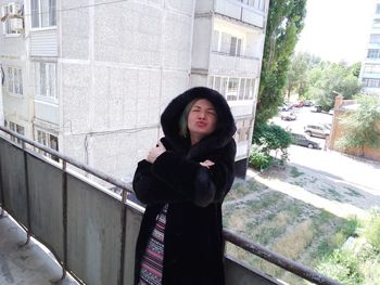 Portrait of woman standing against railing