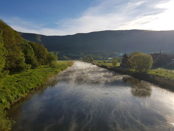 Scenic view of river amidst trees against sky