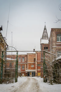 Houses by snow covered buildings against sky