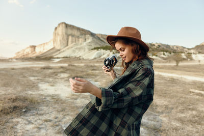 Side view of young woman standing against sky