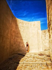 Woman with shadow on wall against sky