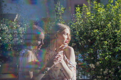 Young woman looking away while showing mobile phone to friend