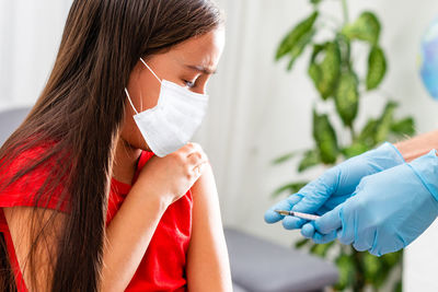 Girl taking vaccination on arm in clinic