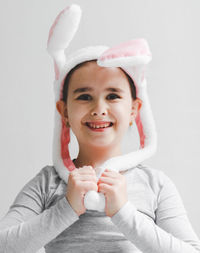 A little happy and smiling caucasian girl in a gray turtleneck with a bunny headband