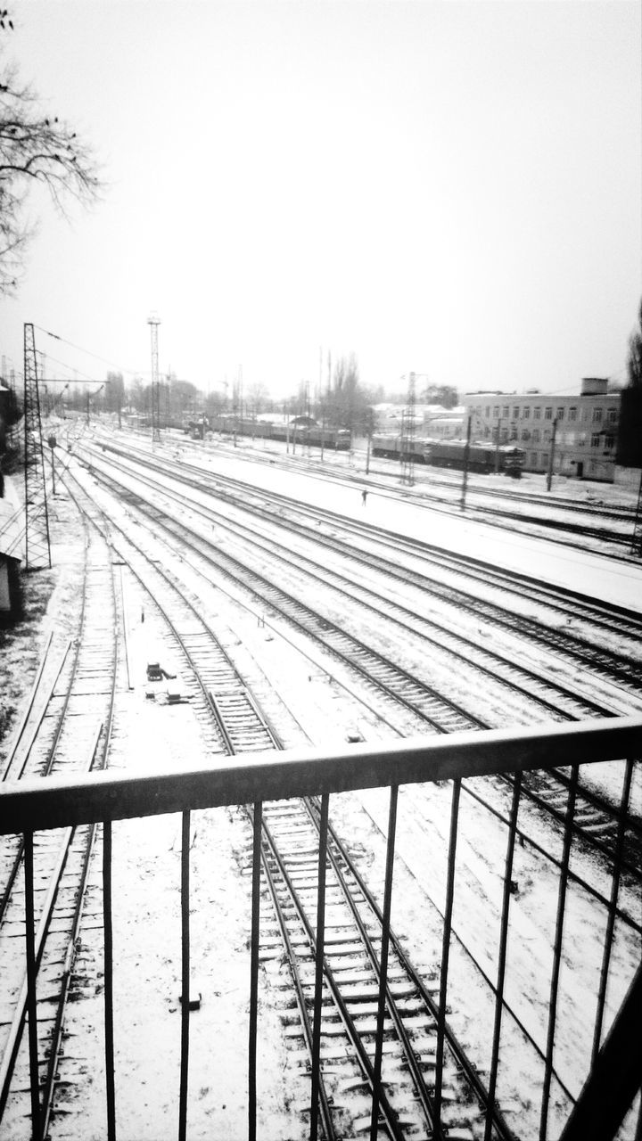 railroad track, transportation, rail transportation, clear sky, railroad station platform, public transportation, railroad station, built structure, architecture, sky, railway track, diminishing perspective, winter, the way forward, building exterior, snow, connection, vanishing point, train - vehicle, cold temperature