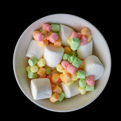 Marshmallows in bowl against black background