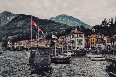 Sailboats moored on river by buildings in city against sky