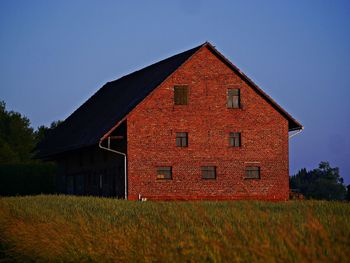 Red house on field against sky