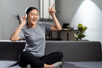 Young woman using mobile phone while sitting at home