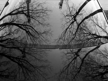 Reflection of bare trees in lake against sky