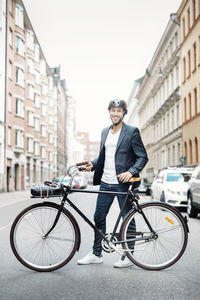 Portrait of happy businessman with bicycle standing on city street