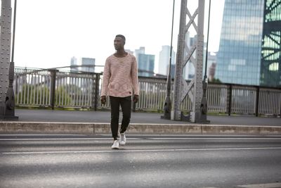 Rear view of man on bridge against sky in city