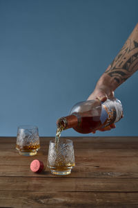 Midsection of person holding wine glass on table