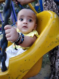 Cute girl sitting on swing in playground