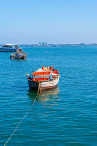 Boat moored in sea against clear blue sky