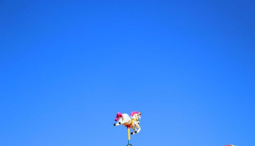 Low angle view of carousel horse against clear blue sky