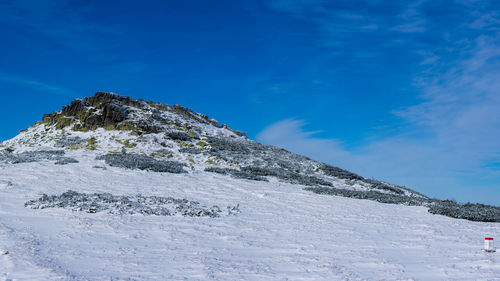 Low angle view of snowcapped mountain against blue sky