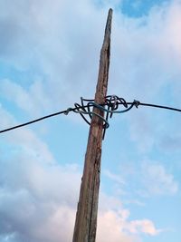 Low angle view of wooden post against sky