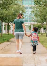 Rear view of woman walking on footpath