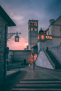 Street amidst buildings in city at sunset