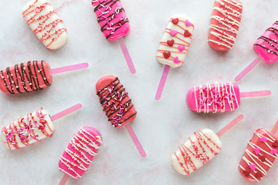 Various valentine decorated cakesicles on a pink marble surface