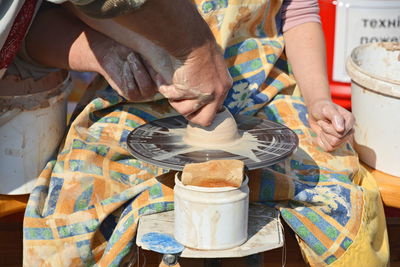 Midsection of woman molding shape on pottery wheel