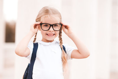Cute girl wearing eyeglasses standing against wall