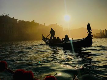 People in gondola on canal during sunset
