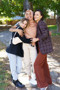 Portrait of smiling friends standing against trees