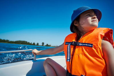 Smiling girl wearing life jacket while sitting in boat