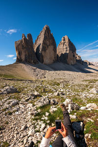 Low section of person on rock in mountains against sky