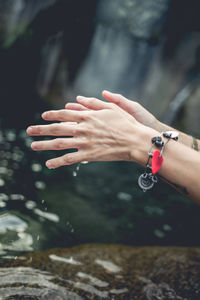 Cropped hands of young woman over lake