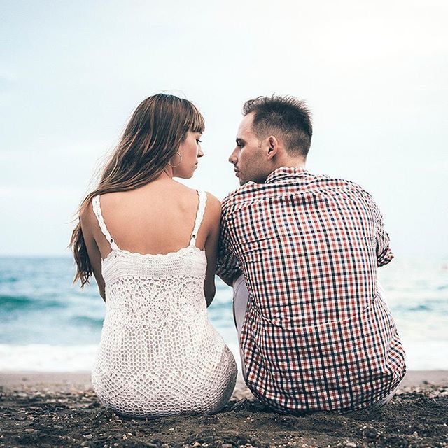 beach, lifestyles, leisure activity, sea, water, casual clothing, shore, standing, sitting, relaxation, togetherness, sand, vacations, rear view, three quarter length, young adult, person, full length