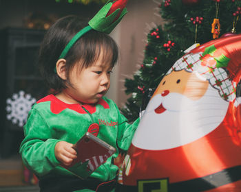 Cute baby girl by christmas decoration at home