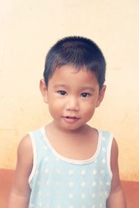 Close-up portrait of boy wearing patterned tank top by wall