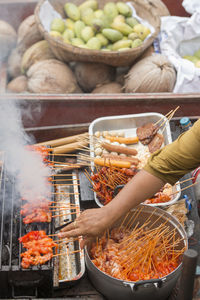 Cropped image of woman preparing street food on barbecue grill