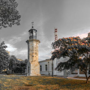 Low angle view of lighthouse by building against sky