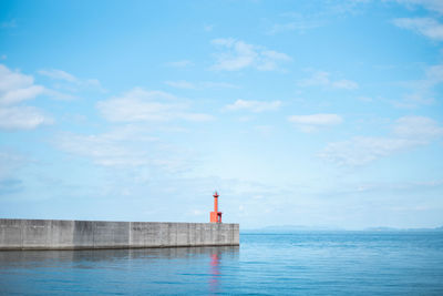 Lighthouse by sea against sky