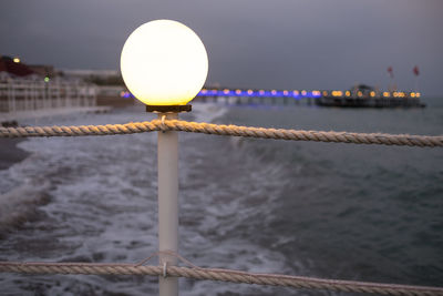 Lit lamp post against calm the river